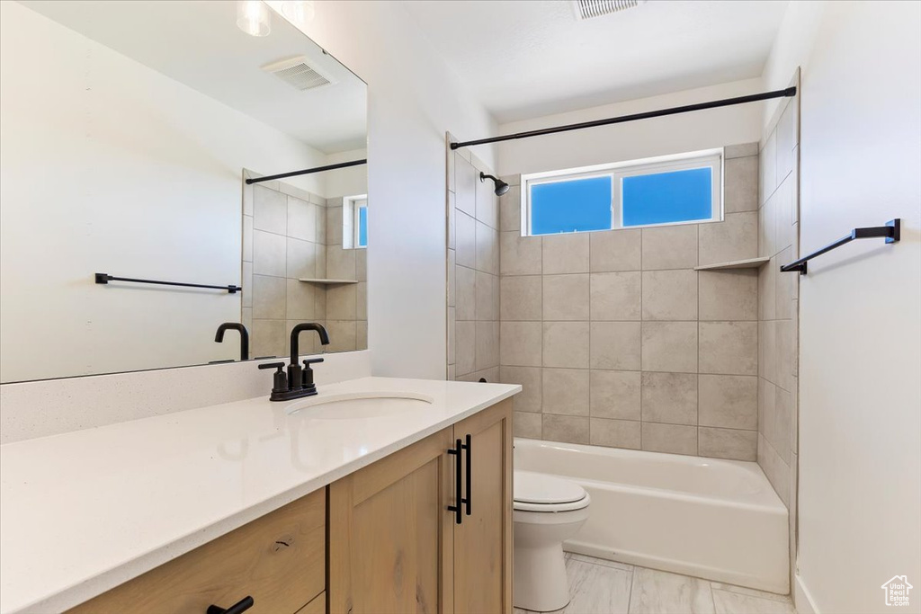 Full bathroom with vanity, toilet, and tiled shower / bath