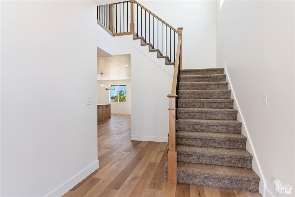 Staircase featuring hardwood / wood-style floors and an inviting chandelier