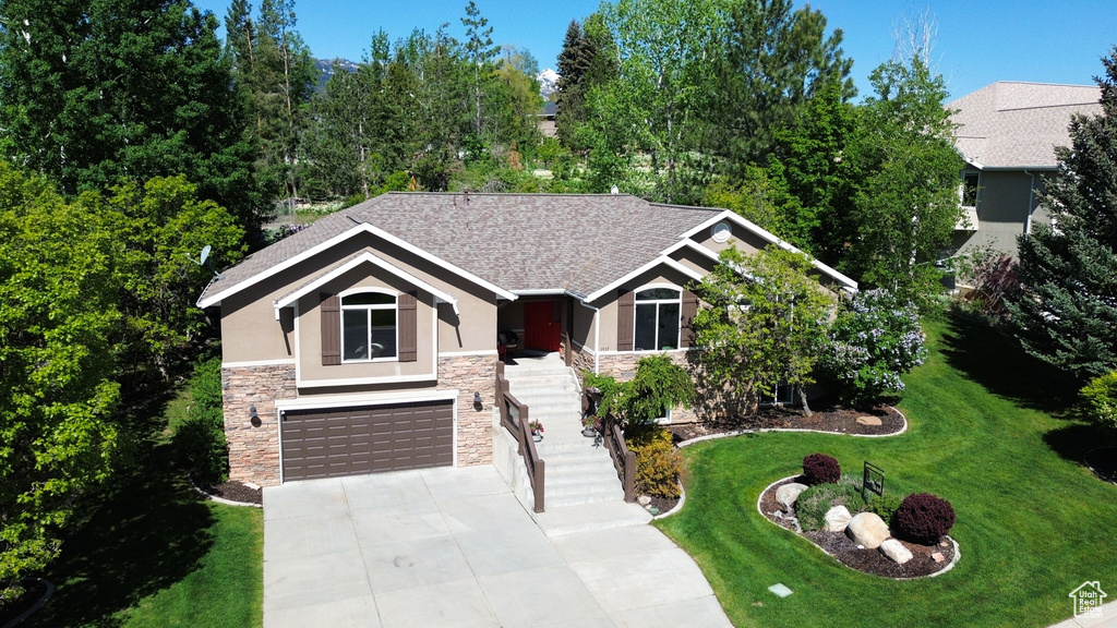 View of front facade with stone siding, stucco siding, stairway, and driveway