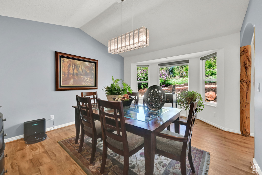 Dining area with vaulted ceiling, light wood-style floors, and baseboards