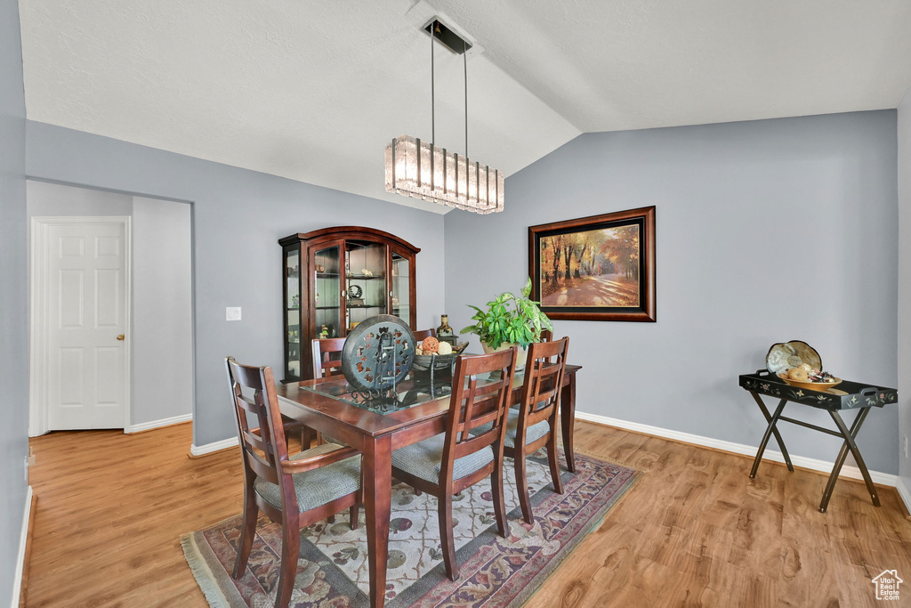 Dining room with lofted ceiling, light wood-style floors, and baseboards