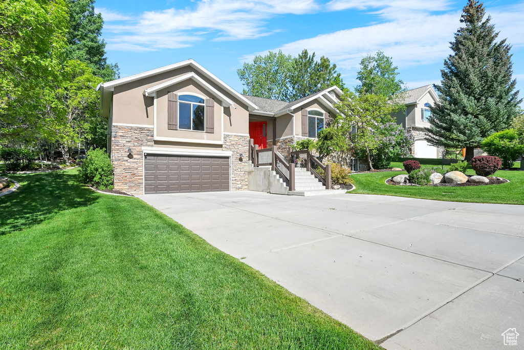 View of front of house featuring stone siding, stucco siding, an attached garage, concrete driveway, and a front yard