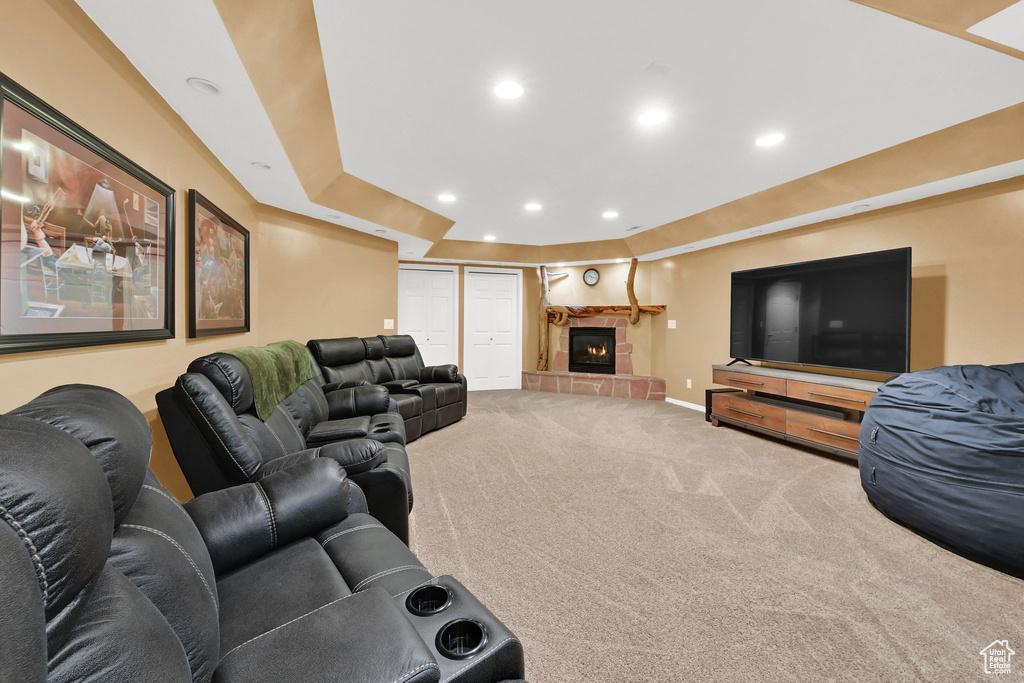 Carpeted living area featuring baseboards, a tray ceiling, recessed lighting, and a tile fireplace