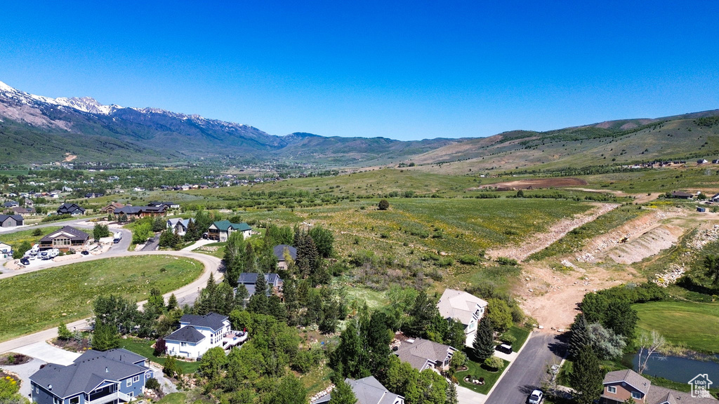Aerial view of property and surrounding area with a mountain backdrop and nearby suburban area
