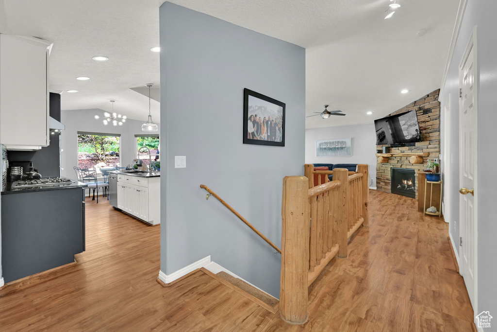 Corridor featuring an upstairs landing, vaulted ceiling, light wood finished floors, baseboards, and recessed lighting