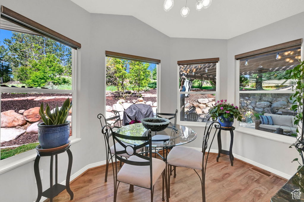 Dining space with wood finished floors, a chandelier, baseboards, and vaulted ceiling