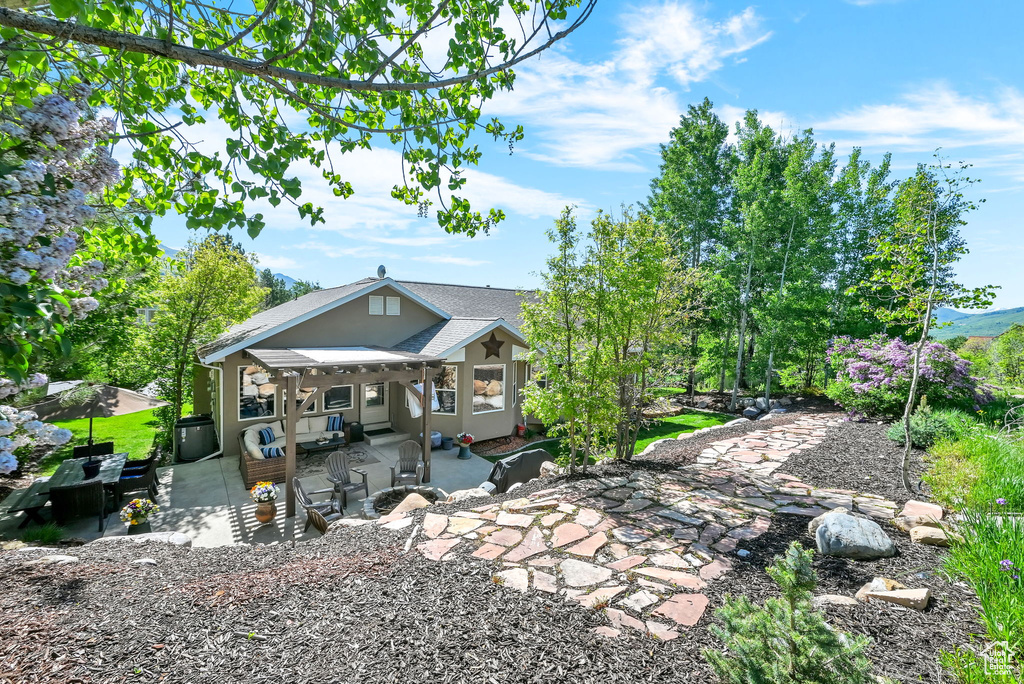 Rear view of property featuring a patio, stucco siding, and a shingled roof