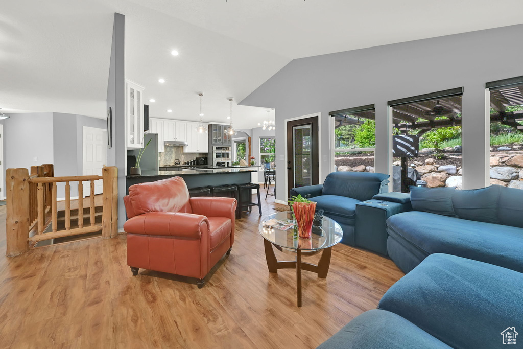 Living room featuring light wood finished floors, lofted ceiling, recessed lighting, and a chandelier
