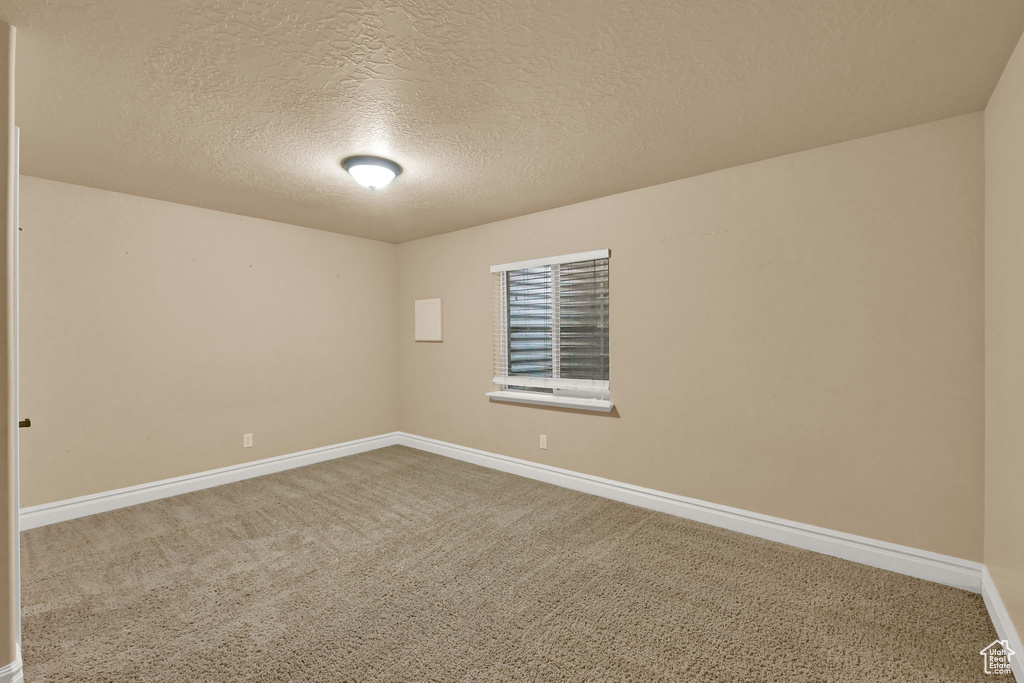 Unfurnished room with a textured ceiling and carpet floors