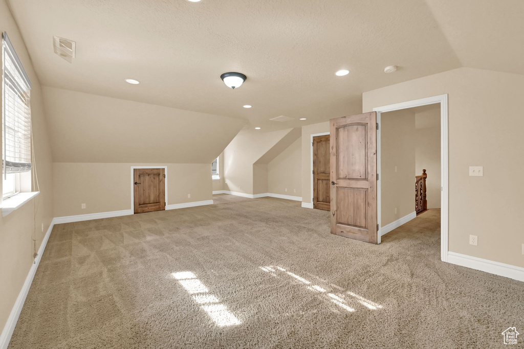 Bonus room featuring vaulted ceiling and light colored carpet