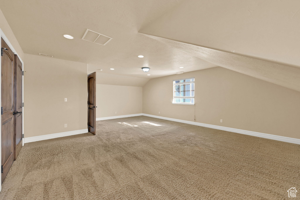 Additional living space with a textured ceiling, carpet, and vaulted ceiling