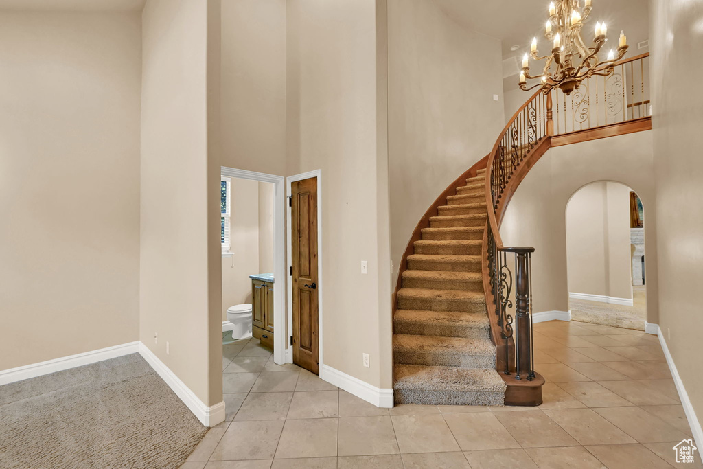 Staircase with a notable chandelier, a towering ceiling, and tile patterned flooring