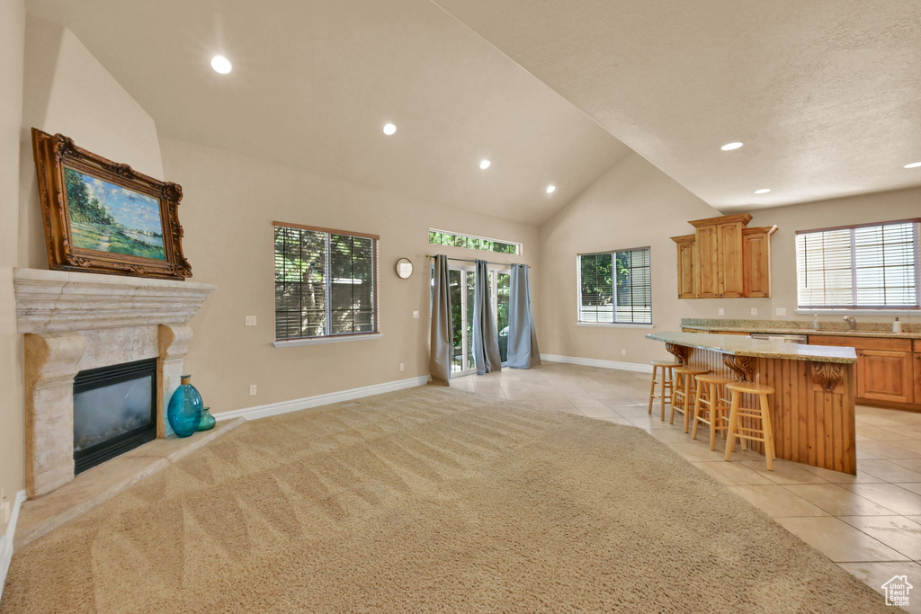 Kitchen with light tile patterned flooring, a center island, a kitchen bar, and a wealth of natural light