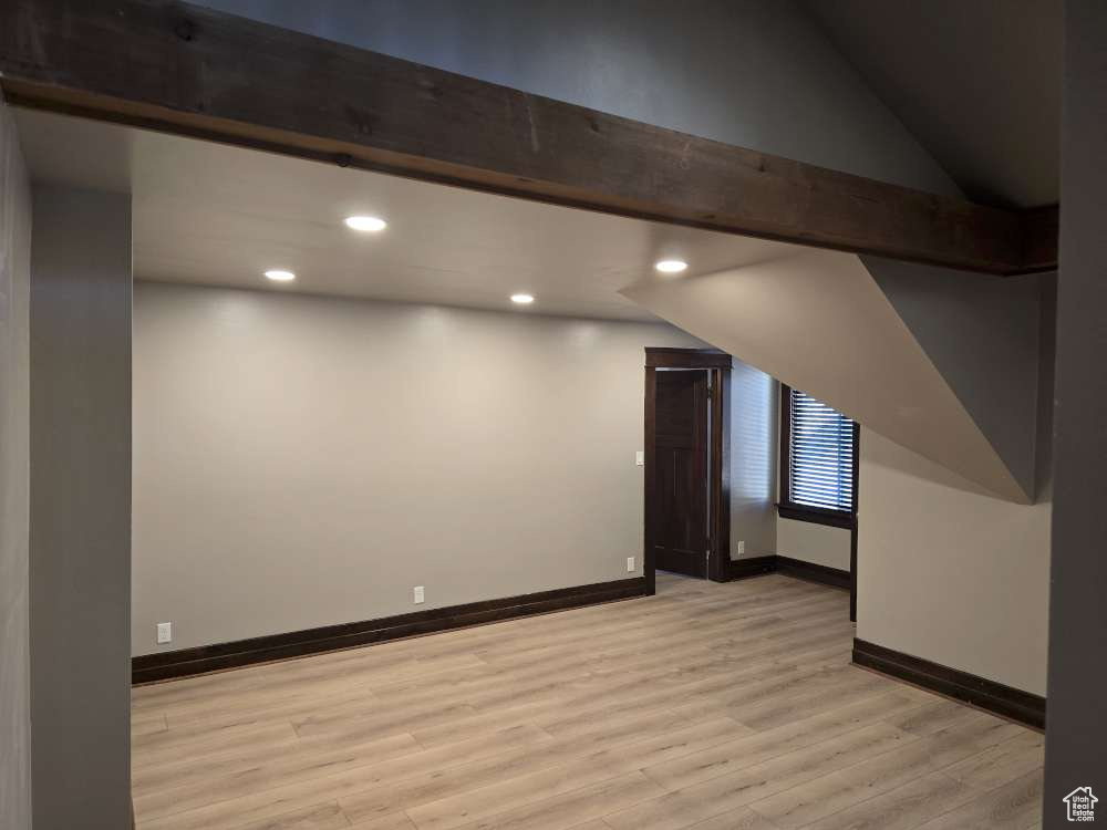 Bonus room with vaulted ceiling with beams and light wood-type flooring