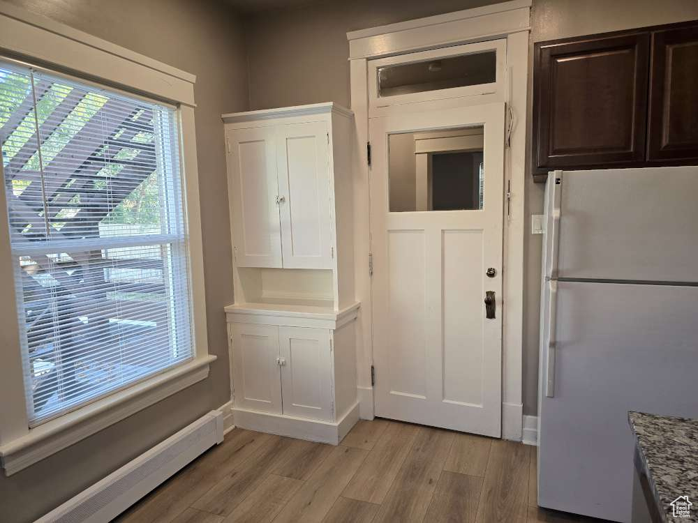 Interior space featuring baseboard heating and light hardwood / wood-style floors