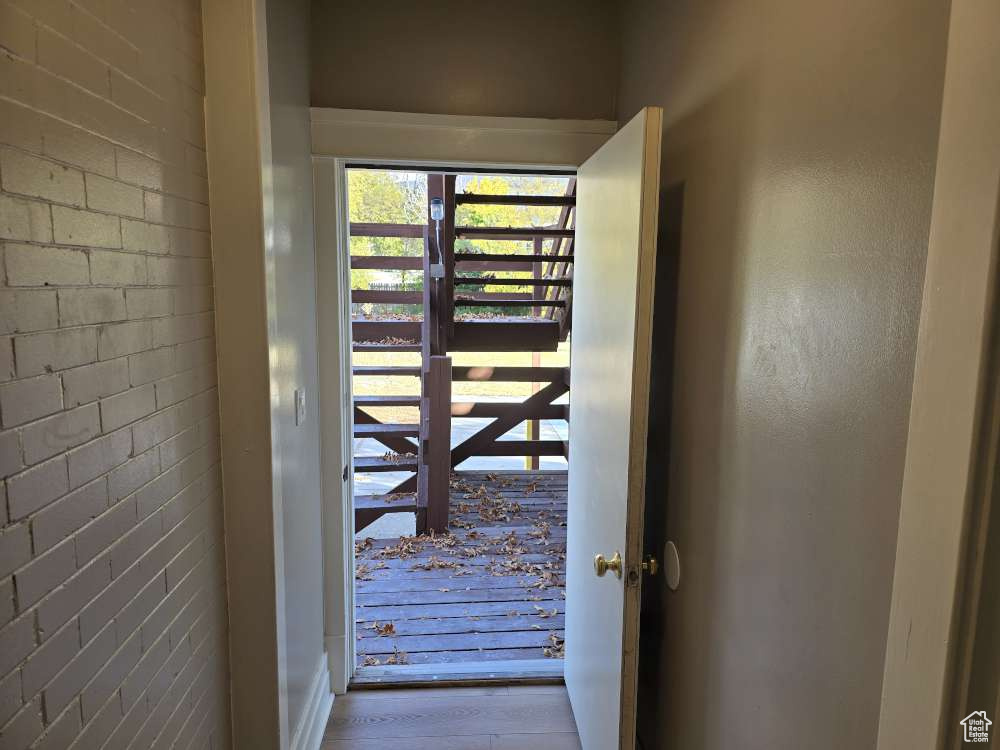 Doorway with brick wall and light wood-type flooring