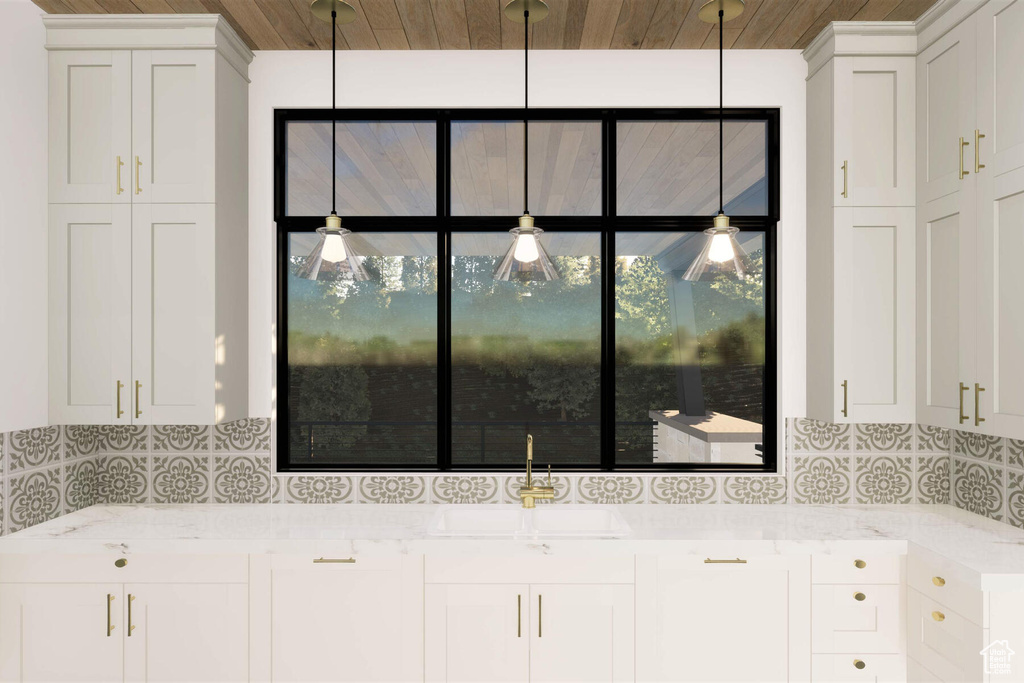 Kitchen featuring sink, white cabinetry, light stone counters, and backsplash