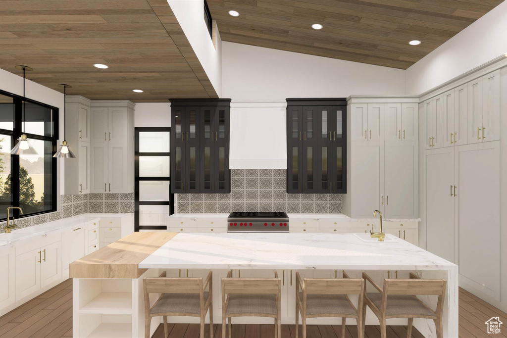 Kitchen featuring lofted ceiling, stainless steel range, wood-type flooring, backsplash, and white cabinetry