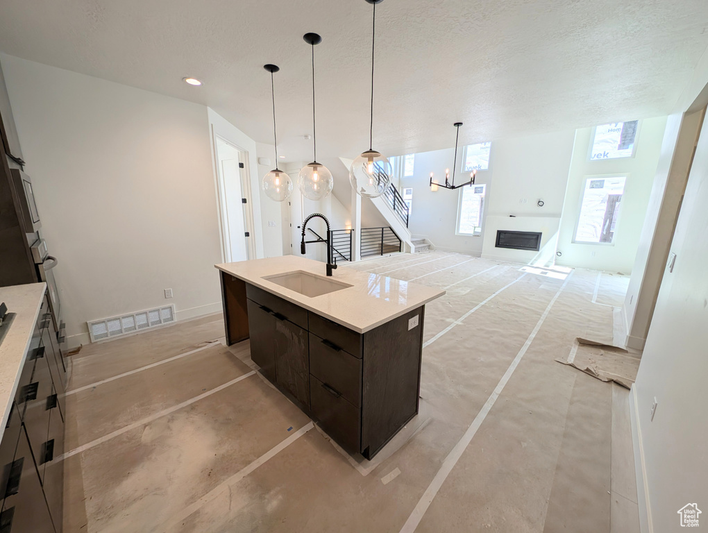 Kitchen with visible vents, dark brown cabinets, a sink, light countertops, and a chandelier