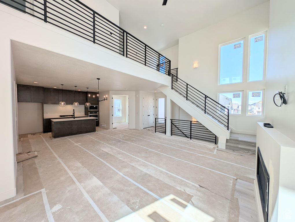 Unfurnished living room featuring a towering ceiling and stairway