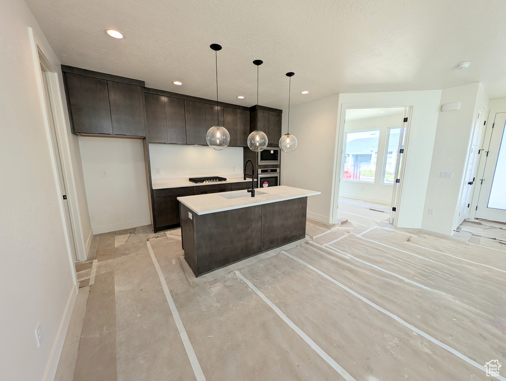 Kitchen with built in microwave, dark brown cabinets, baseboards, black cooktop, and stainless steel oven