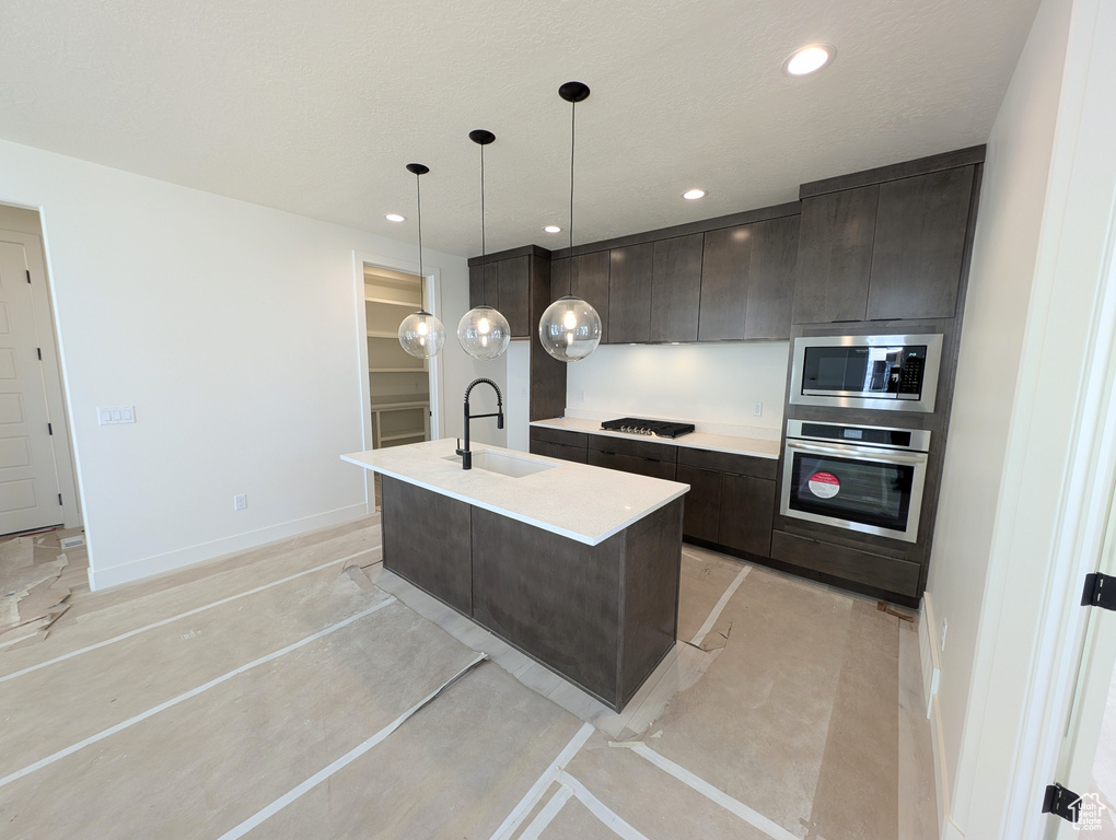 Kitchen with a sink, modern cabinets, dark brown cabinetry, and stainless steel appliances