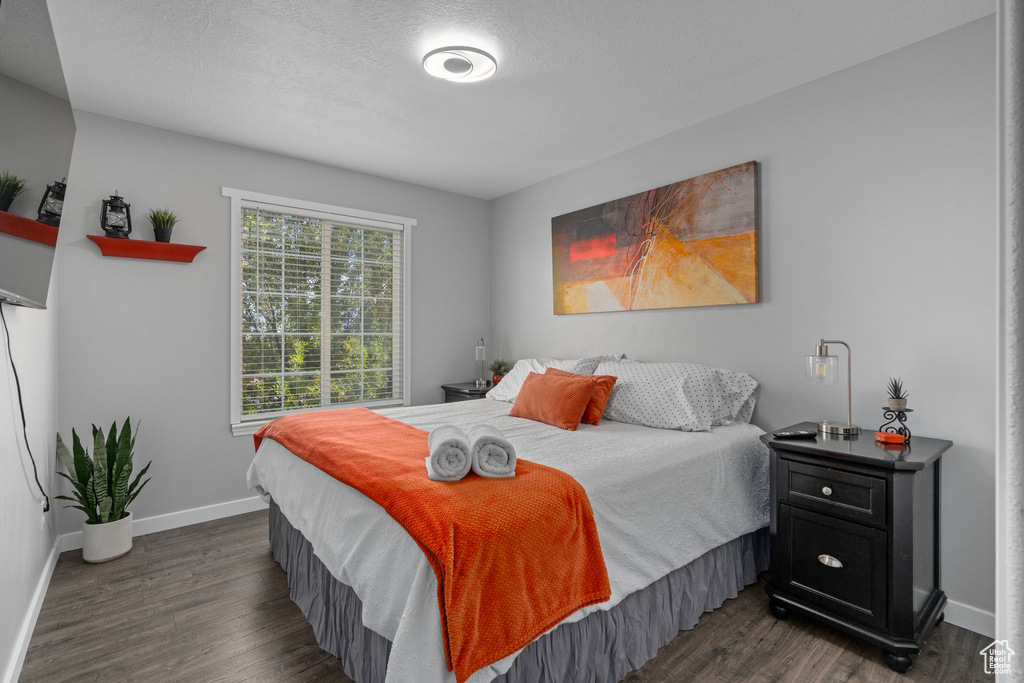 Bedroom with a textured ceiling and dark hardwood / wood-style flooring