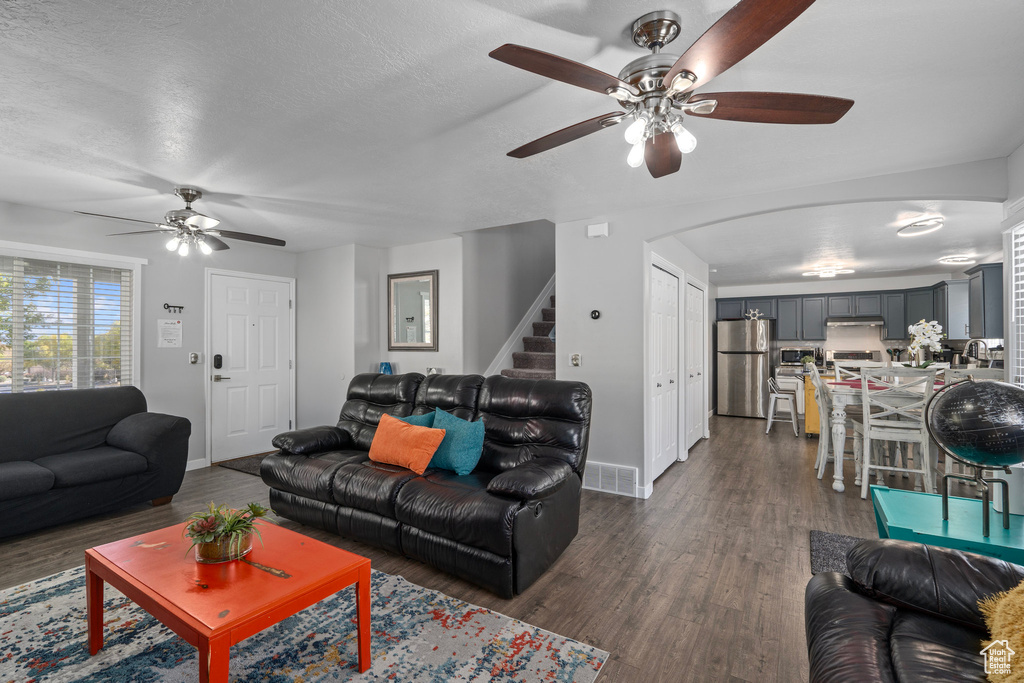 Living room featuring sink, dark wood-type flooring, a textured ceiling, and ceiling fan