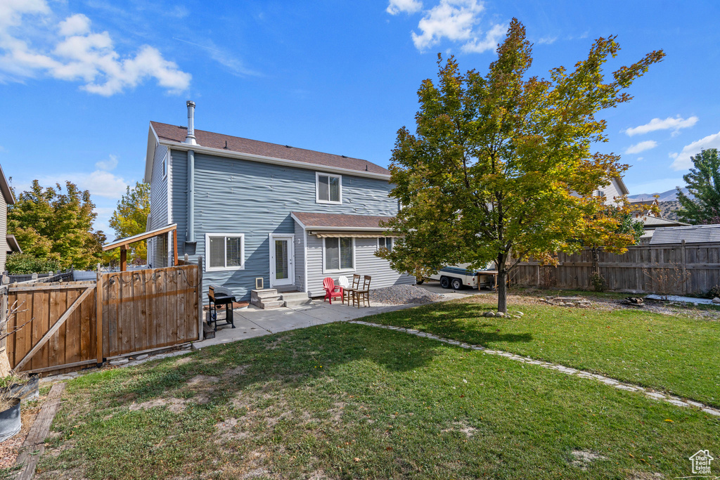 Back of house with a patio area and a lawn