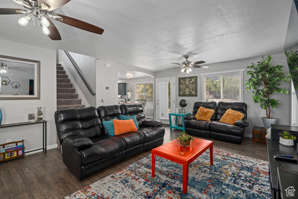 Living room featuring dark wood-type flooring, a textured ceiling, and ceiling fan