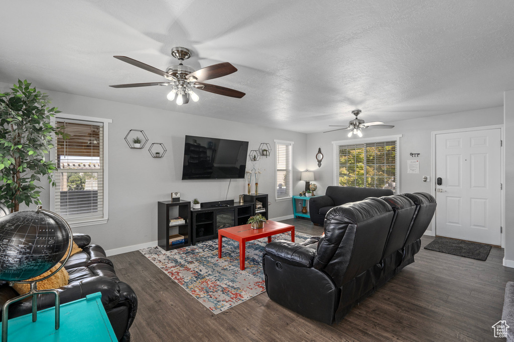 Living room with ceiling fan, a textured ceiling, and dark hardwood / wood-style floors