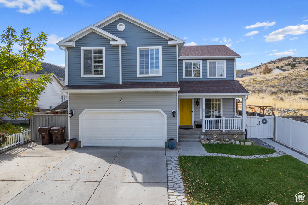 Front facade featuring a front yard, a garage, a mountain view, and a porch