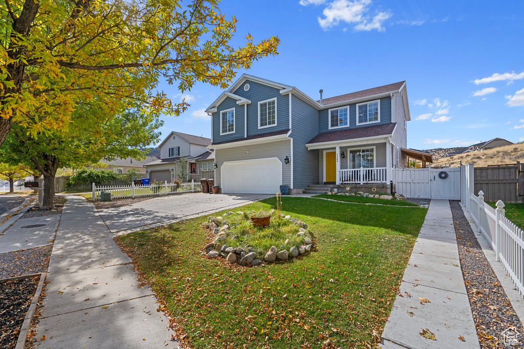 View of property with a porch, a front lawn, and a garage