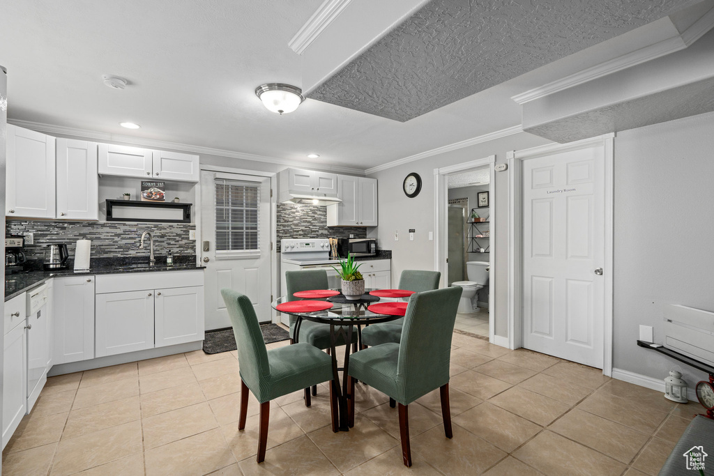 Tiled dining area with ornamental molding, a textured ceiling, and sink