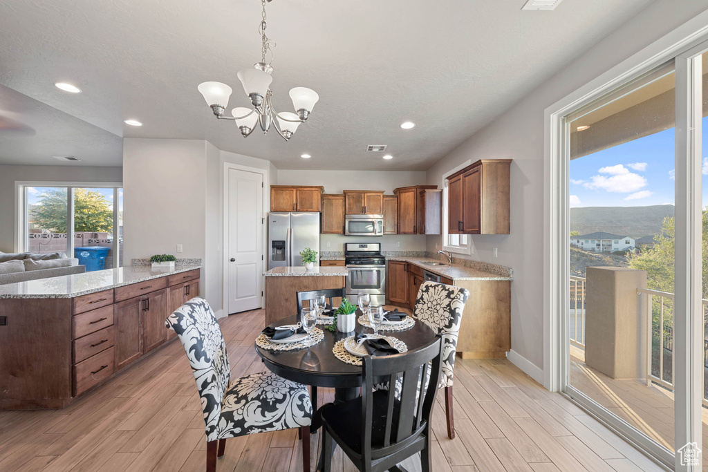 Dining space featuring sink, a notable chandelier, and light hardwood / wood-style flooring