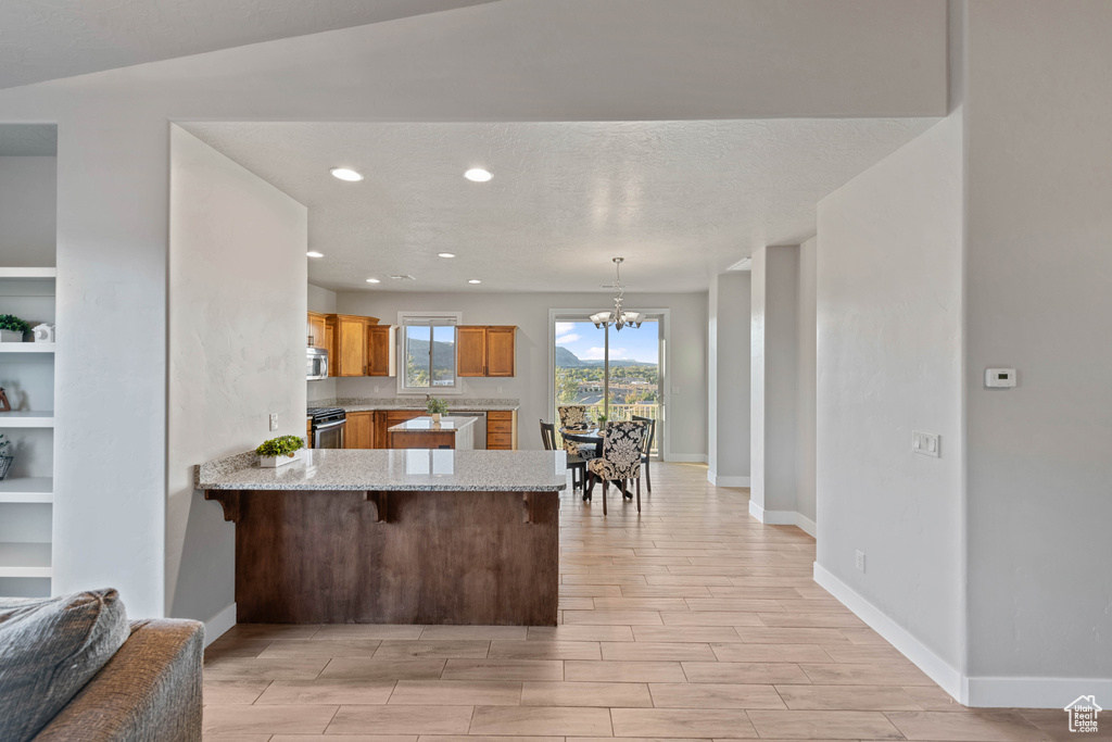 Kitchen with a kitchen breakfast bar, hanging light fixtures, kitchen peninsula, a chandelier, and light hardwood / wood-style floors