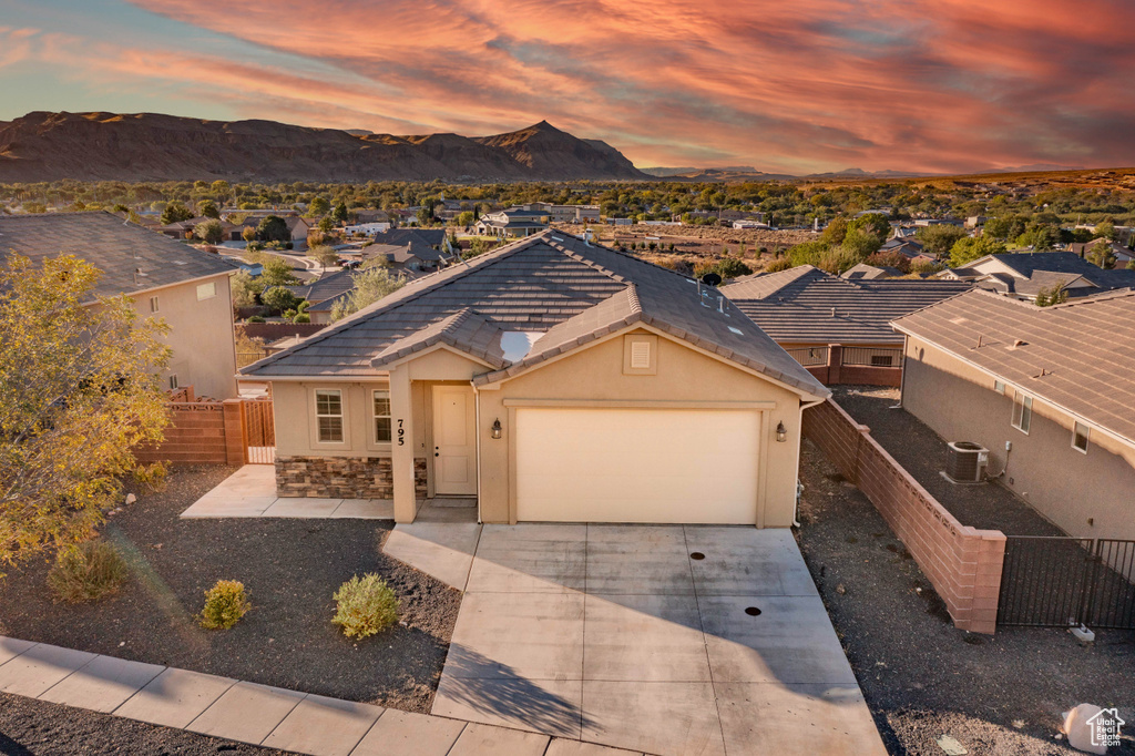 View of front of property featuring cooling unit, a garage, and a mountain view