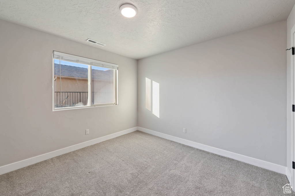 Carpeted spare room with a textured ceiling