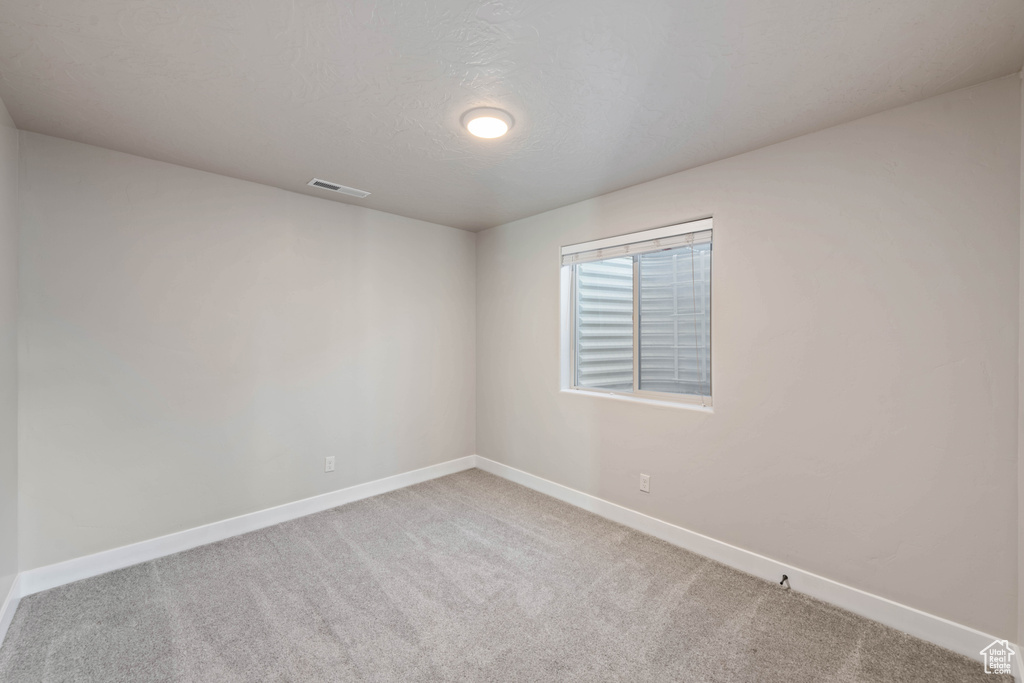 Carpeted empty room featuring a textured ceiling