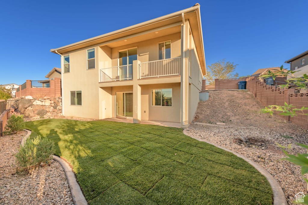 Back of house with a lawn and a balcony