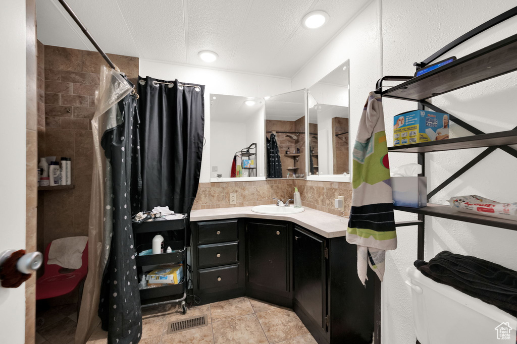 Bathroom featuring tasteful backsplash, toilet, tile patterned floors, a shower with curtain, and vanity