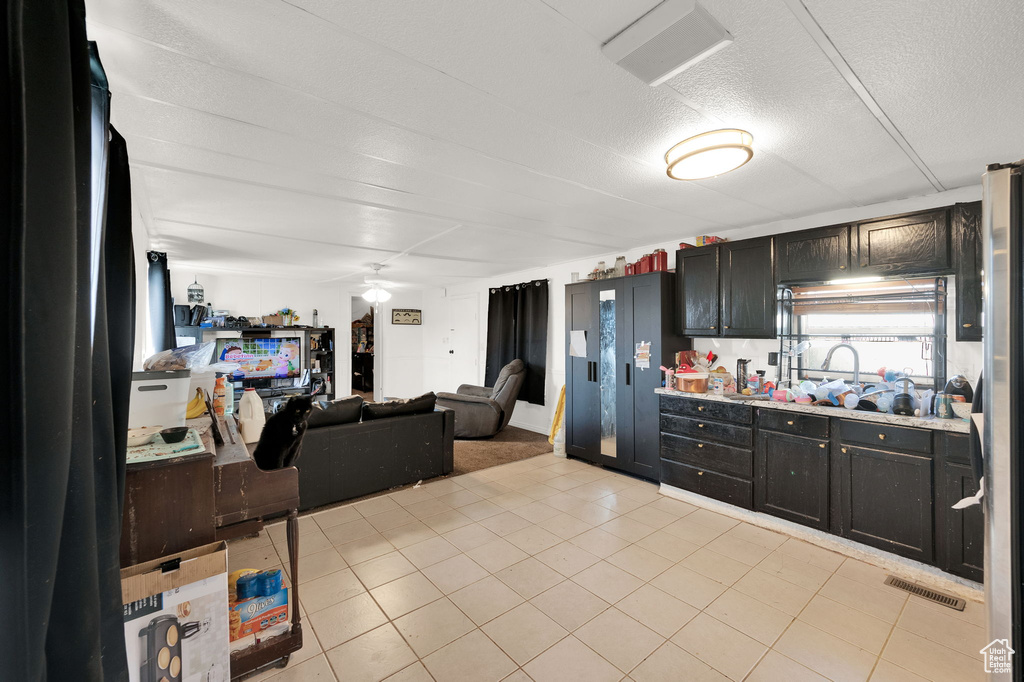 Kitchen with a textured ceiling, light tile patterned flooring, sink, and ceiling fan