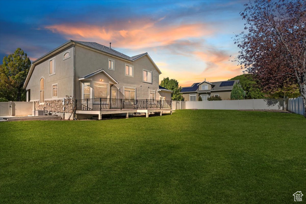 Rear view of house with stucco siding, a fenced backyard, and a deck