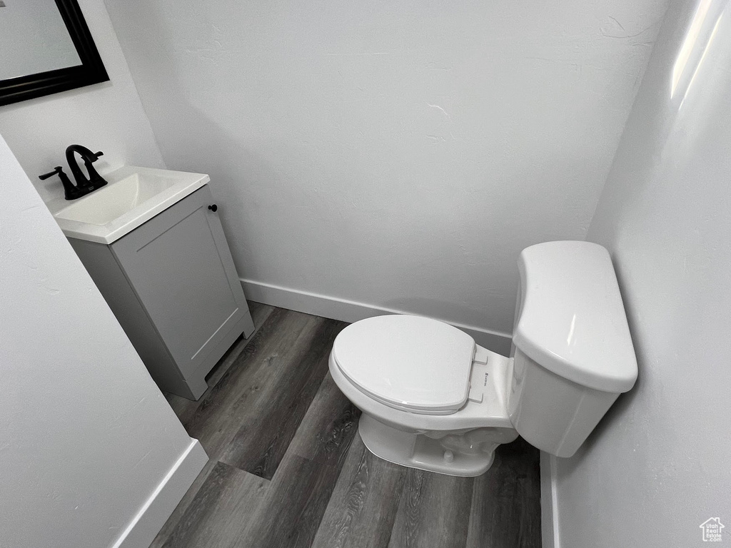 Bathroom featuring toilet, vanity, and wood-type flooring