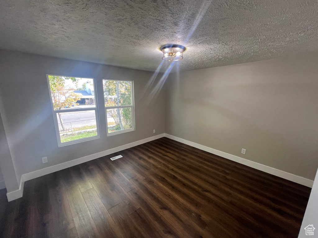 Spare room featuring a textured ceiling and dark hardwood / wood-style flooring