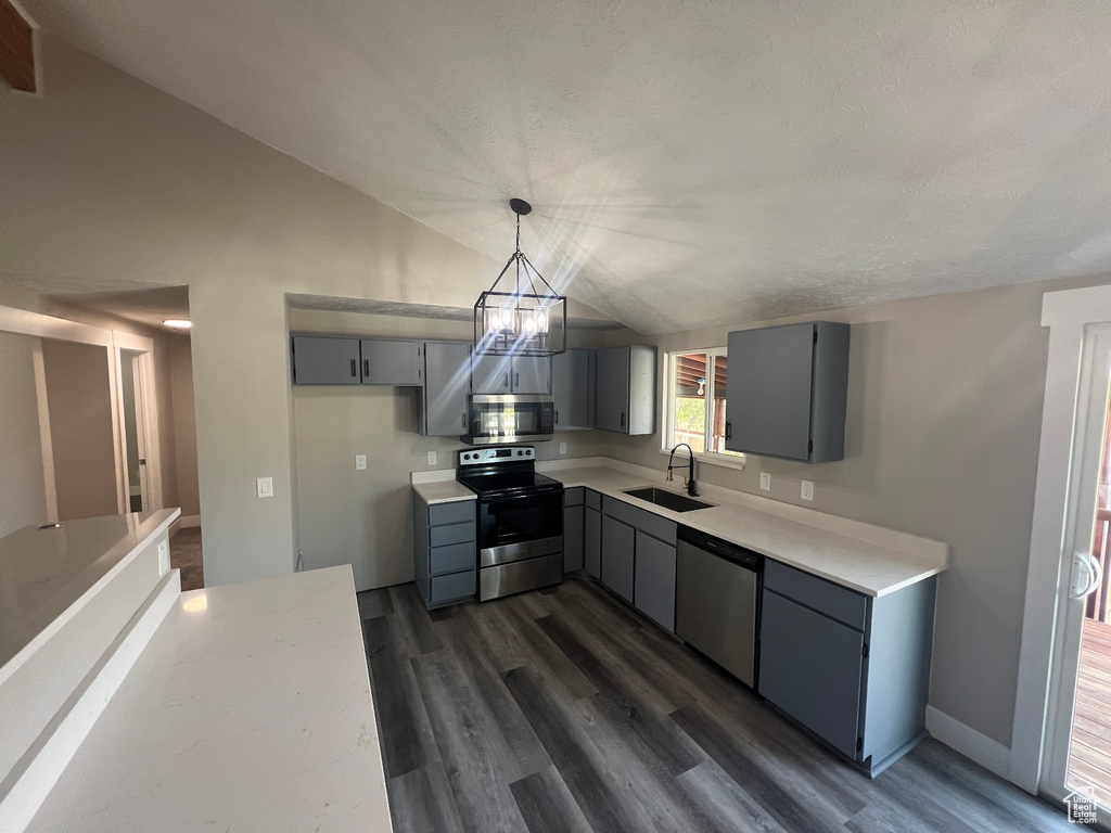 Kitchen featuring gray cabinetry, sink, stainless steel appliances, lofted ceiling, and pendant lighting