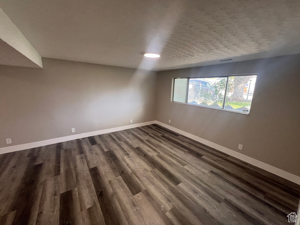 Empty room featuring dark hardwood / wood-style floors and a textured ceiling