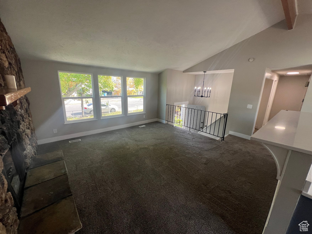 Living room with vaulted ceiling with beams, an inviting chandelier, carpet floors, and a fireplace