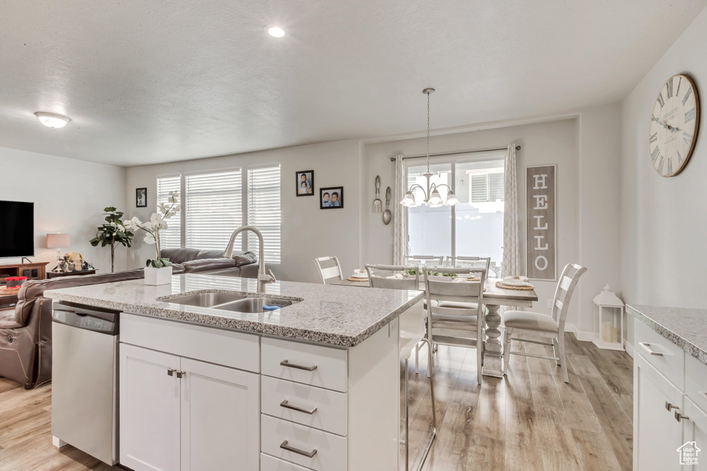 Kitchen featuring dishwasher, hanging light fixtures, sink, white cabinetry, and light hardwood / wood-style floors