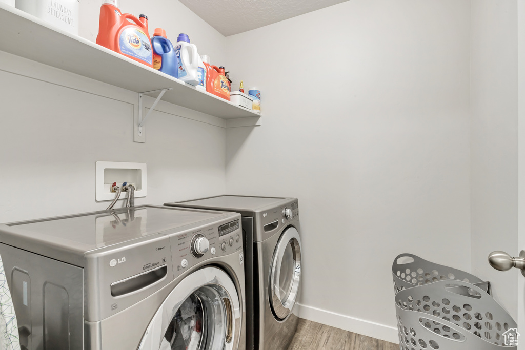 Washroom with washer and dryer and light hardwood / wood-style flooring